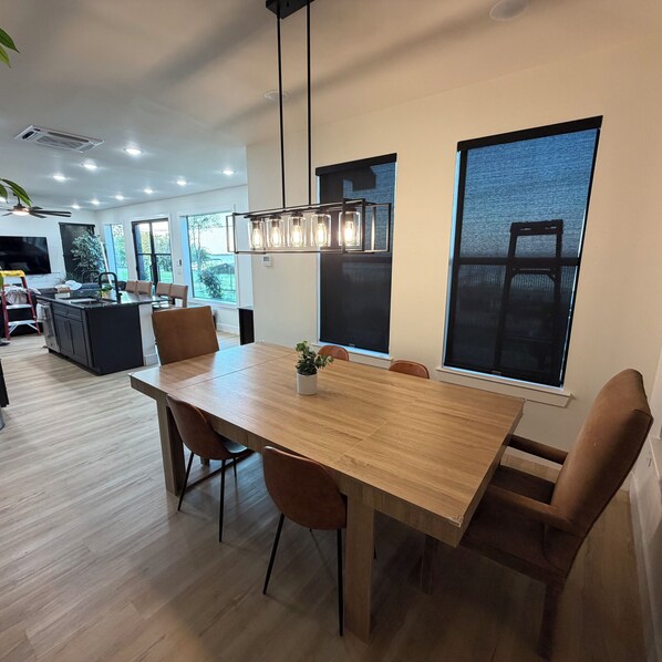 A modern dining area with a wooden table, chairs, and pendant lighting.