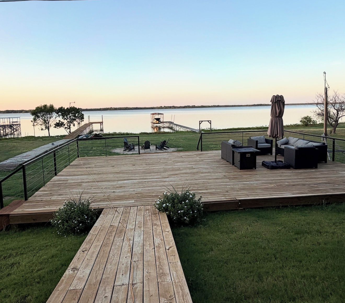 Un terrazzo in legno con mobili da esterno, una zona relax coperta e vista sull'acqua.