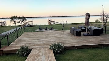 Un terrazzo in legno con mobili da esterno, una zona relax coperta e vista sull'acqua.