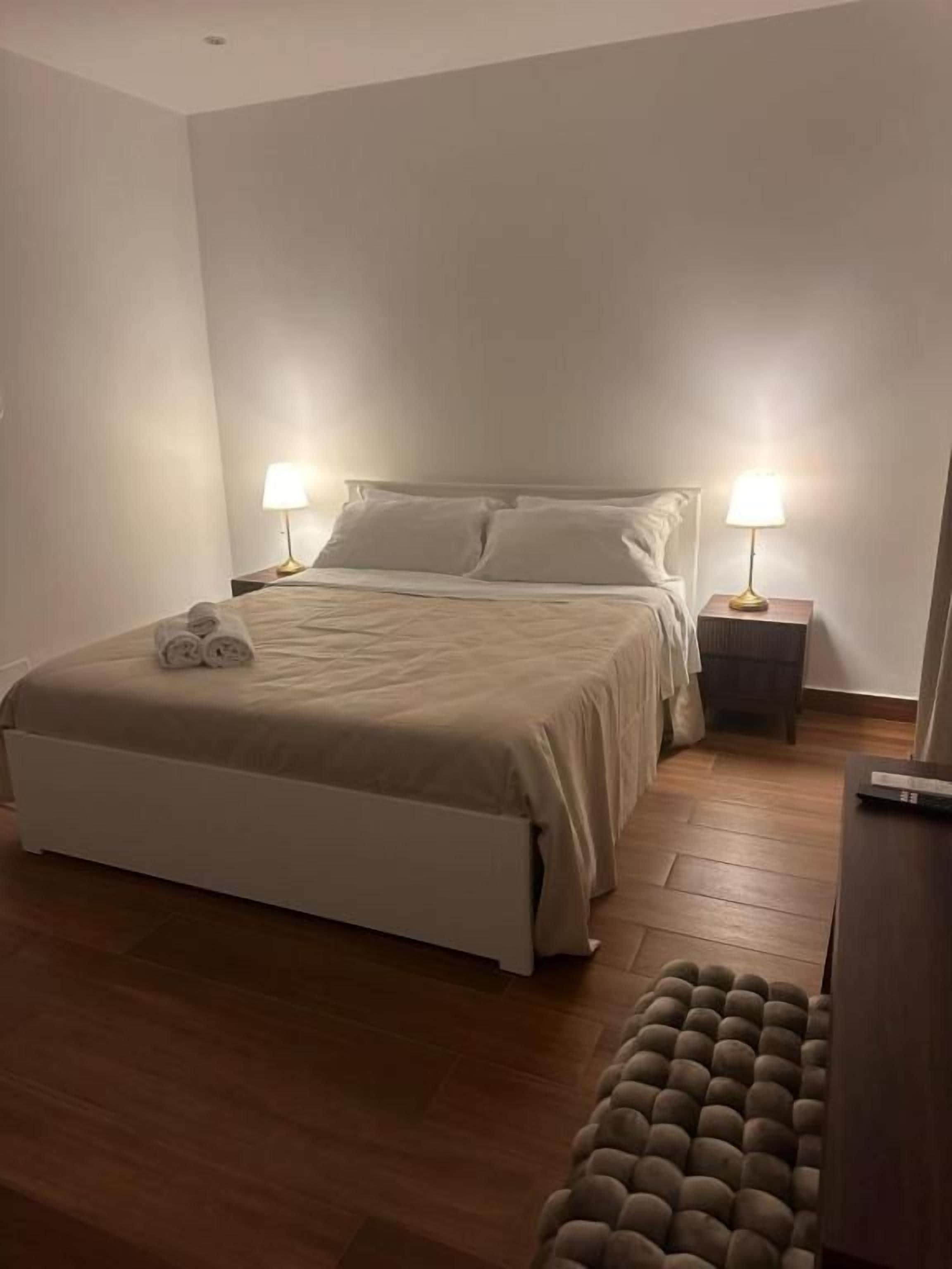 Une chambre à coucher avec un lit, des lampes de chevet, un plancher en bois et un banc.
