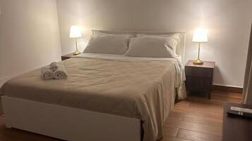 Ein Schlafzimmer mit einem Bett, Nachttischlampen, Holzboden und einer Bank.
