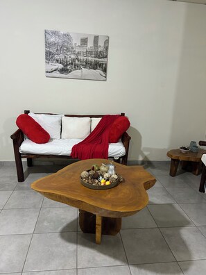 A living room with a wooden coffee table, a sofa with red cushions, and a framed black and white photo on the wall. - Cozy 2-bedroom apartment in fantastic Santa Ana  El Salvador with AC (Santa Ana)