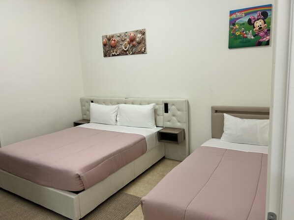 A bedroom with two beds, a nightstand, a wall-mounted artwork, and a cartoon character poster.