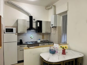 A compact kitchen with a microwave, stove, and cabinets. - AntoBel House Milan – Private Apartment for 4 Guests Near the Metro (Milano)