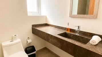 A bathroom with a toilet, sink, and mirror.