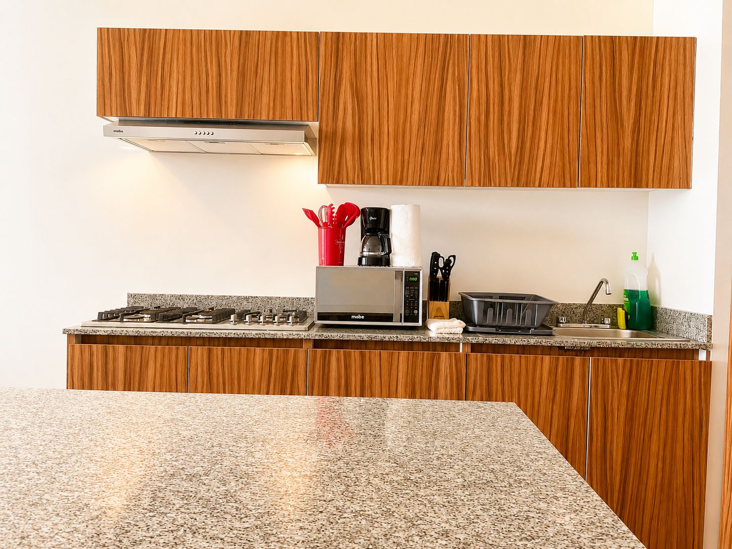 A modern kitchen with wooden cabinets, a gas stove, a microwave, and a toaster.