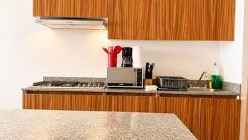 A modern kitchen with wooden cabinets, a gas stove, a microwave, and a toaster.