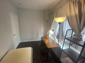 A room with a desk, a chair, a lamp, a window with curtains, and a door. - Steps to Main St Subway | 20 Min to Downtown (Toronto)