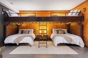 A bunk bed room with wooden walls, a central ladder, and string lights. - Long-Range Lake Views | Sauna, Plunge, Hot Tub (Bellaire)