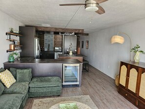 A compact living space with a kitchenette, a sofa, a dining area, and a ceiling fan. - Rising Tides Properties Condo 204 (Murrells Inlet)