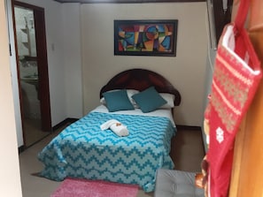 A hotel room with a bed, a painting on the wall, and a bathroom visible through an open door. - Casa Tundama  (Duitama)