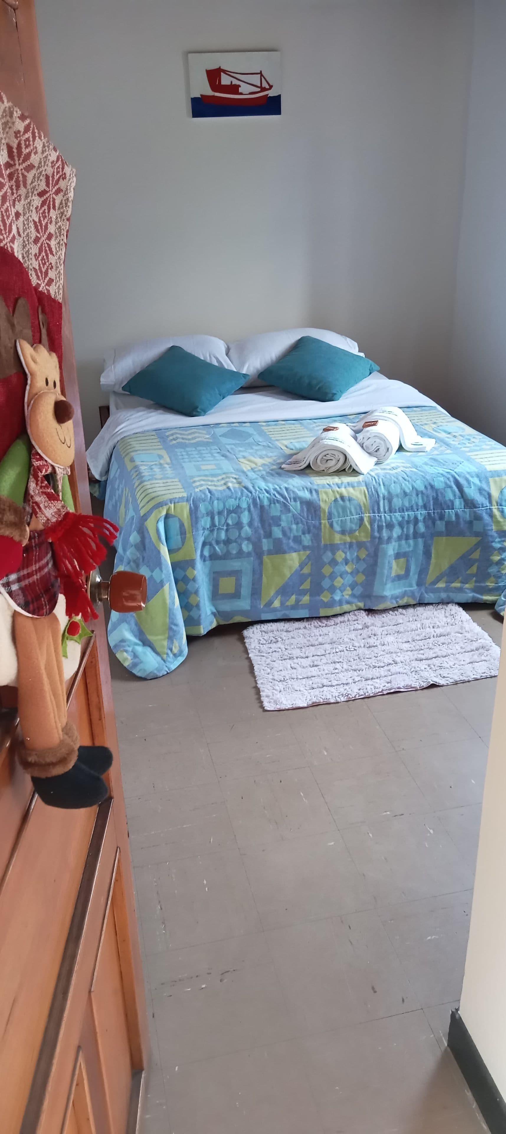 A bedroom with a bed, pillows, a rug, and a wall decoration.