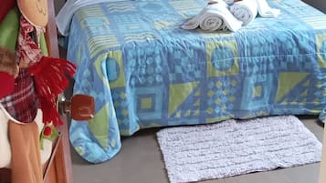 A bedroom with a bed, pillows, a rug, and a wall decoration.