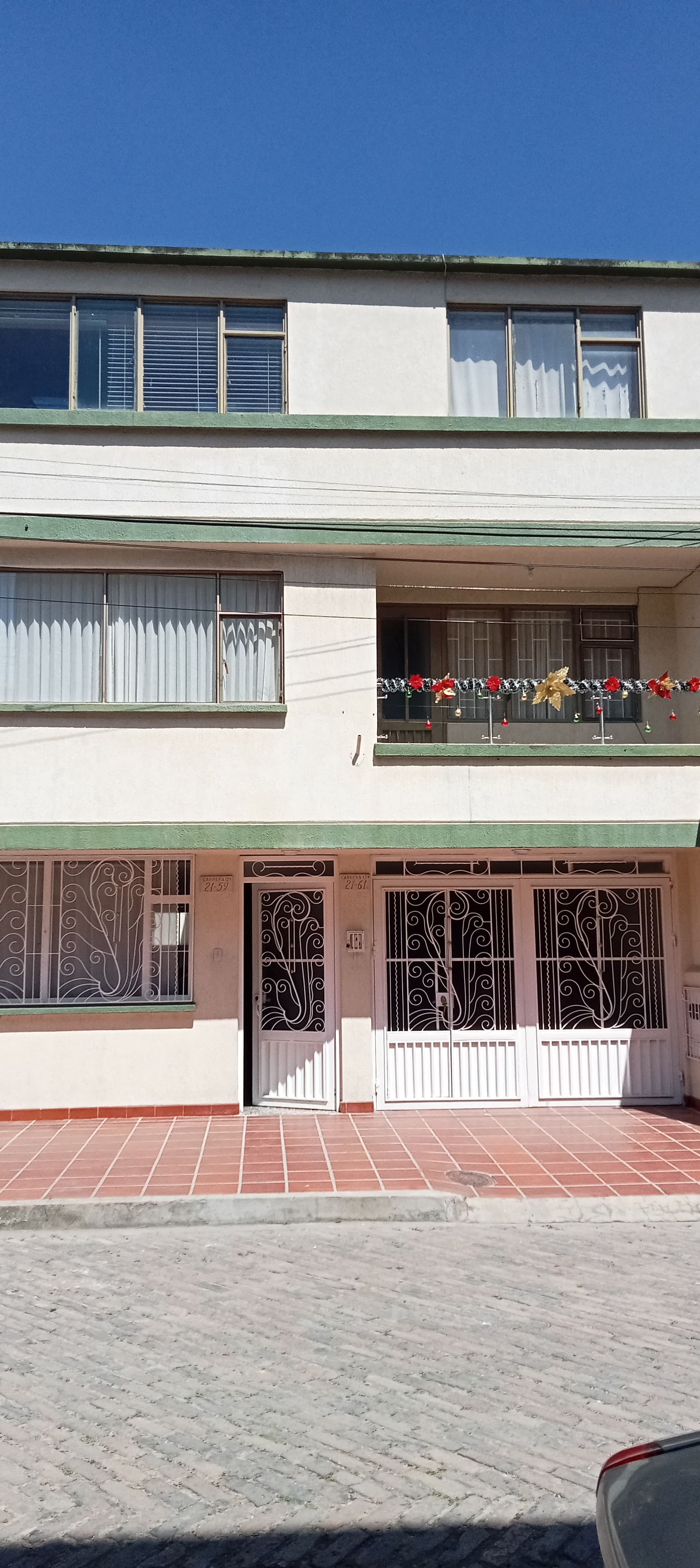 Un edificio de dos plantas con un balcón en el piso superior, que cuenta con barandilla metálica y detalles decorativos.