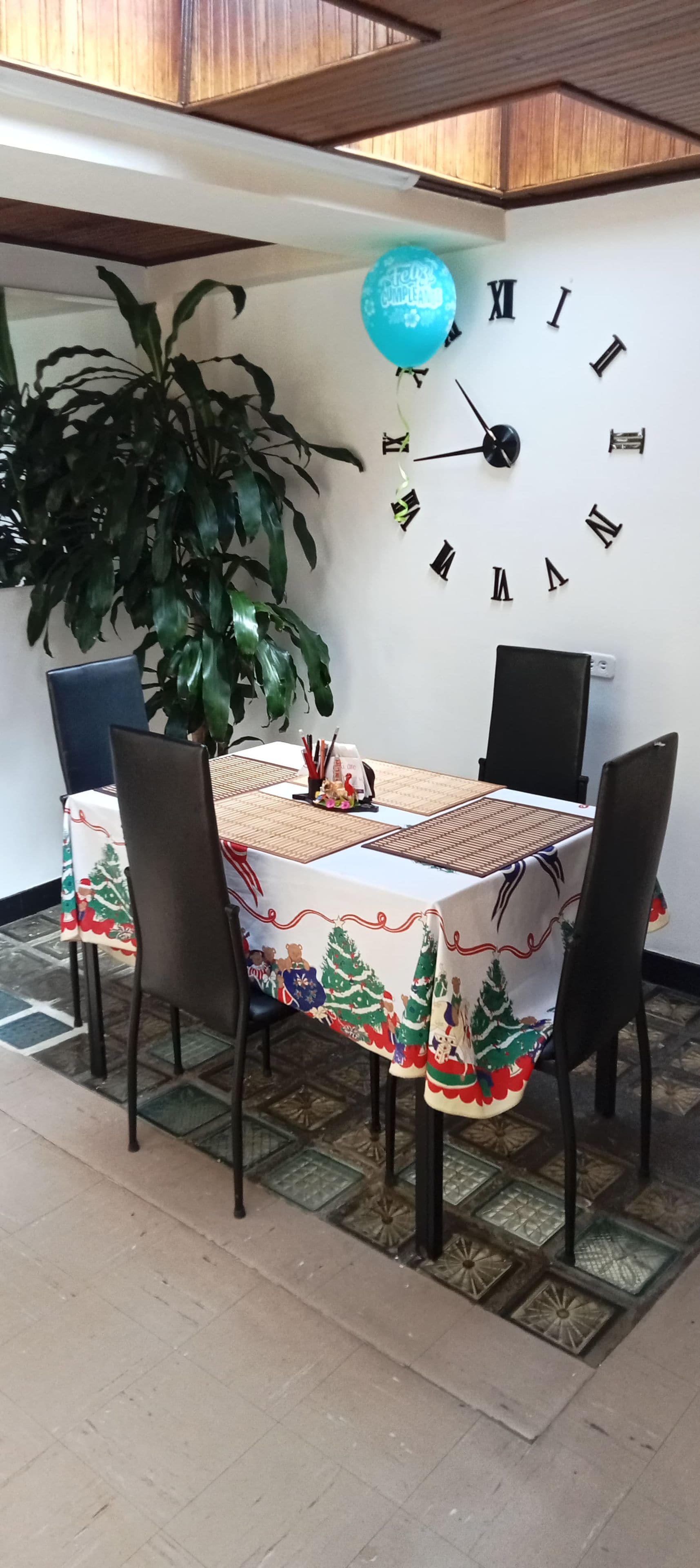 A dining table with chairs, a clock on the wall, and a potted plant.