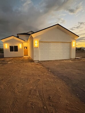 A two-story house with a garage, a driveway, and a dirt lot. - Spacious 4-bedroom new construction house in fantastic Surprise with AC (Surprise)
