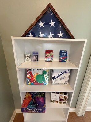 Ein Bücherregal mit verschiedenen Gesellschaftsspielen, darunter UNO, Sequence und Trivia Pursuit.