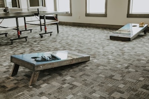 A room with a patterned carpet, a table with chairs, and a bench with cushions.
