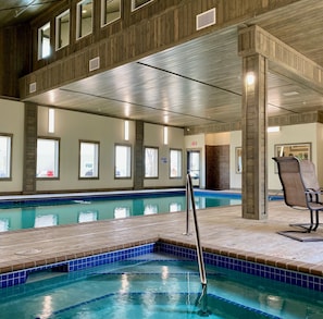 Una piscina interior amb sòl de rajola i escala metàl·lica.