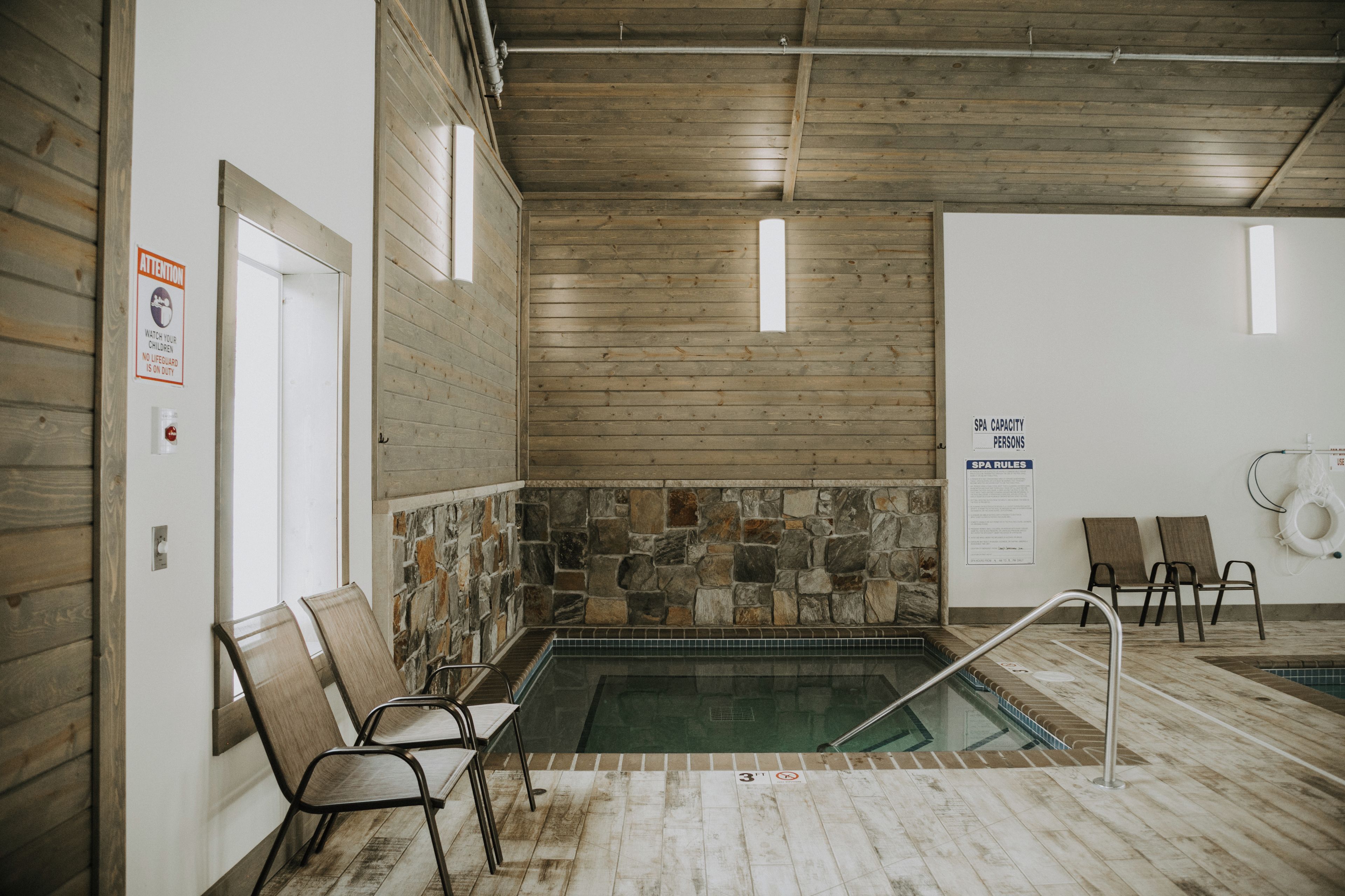Et spaområde med stenvæg, pool og siddepladser.