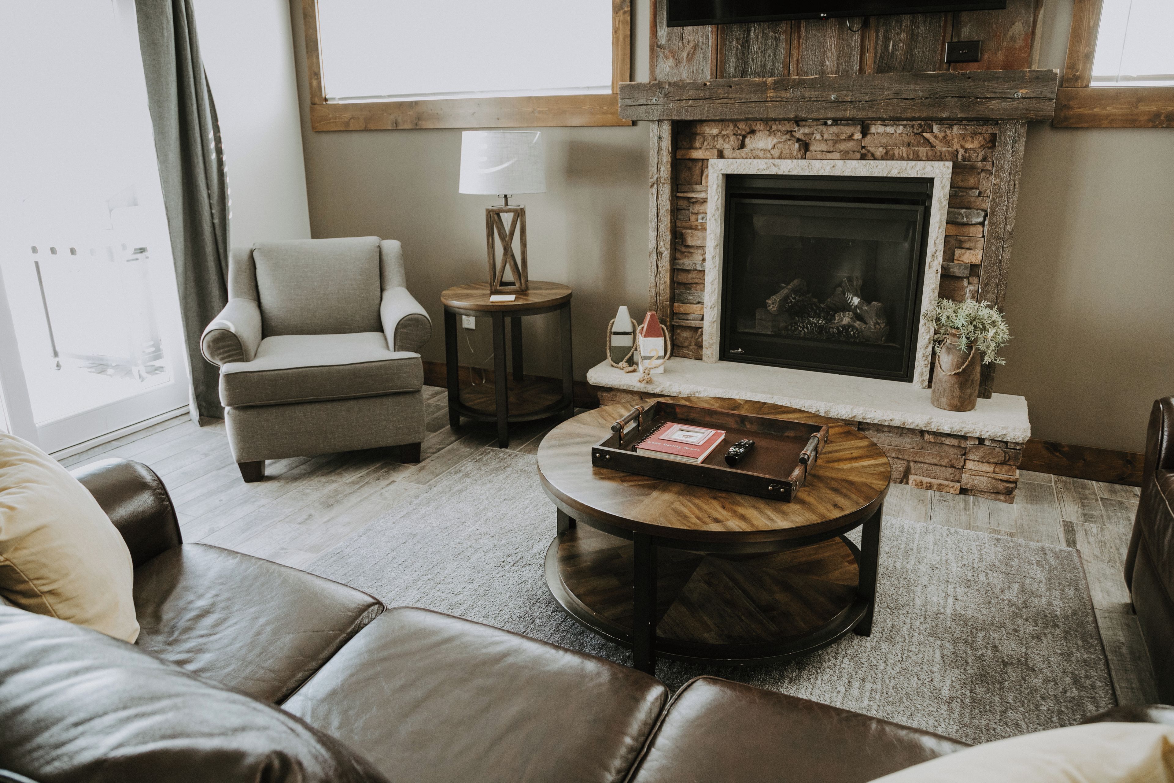 Una sala de estar con chimenea de piedra, muebles de cuero y una mesita auxiliar con lámpara.