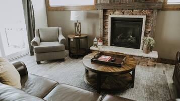 Una sala de estar con chimenea de piedra, muebles de cuero y una mesita auxiliar con lámpara.