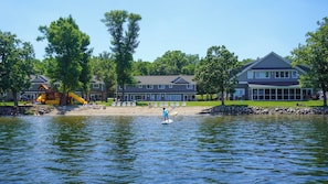 A lakeside property with a dock, a playground, and a large house with a covered patio.
