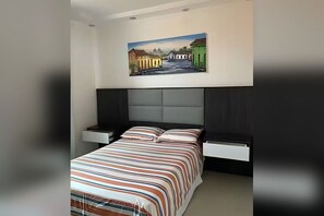 A bedroom with a bed, nightstands, a painting, and a headboard. - Superb 4-bedroom house with AC in Armação dos Búzios (Armação dos Búzios)