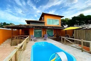 Ein zweistöckiges Gebäude mit Schwimmbad, Außenbereich und einer Hängematte.