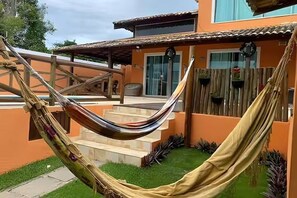 A hammock tied between two wooden posts in a backyard with a house in the background. - Superb 4-bedroom house with AC in Armação dos Búzios (Armação dos Búzios)