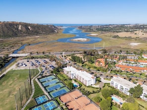 An aerial view of a coastal area with a river, a parking lot, tennis courts, and residential buildings. - Renovated Condo Near Omni La Costa Resort & Golf! (Carlsbad)