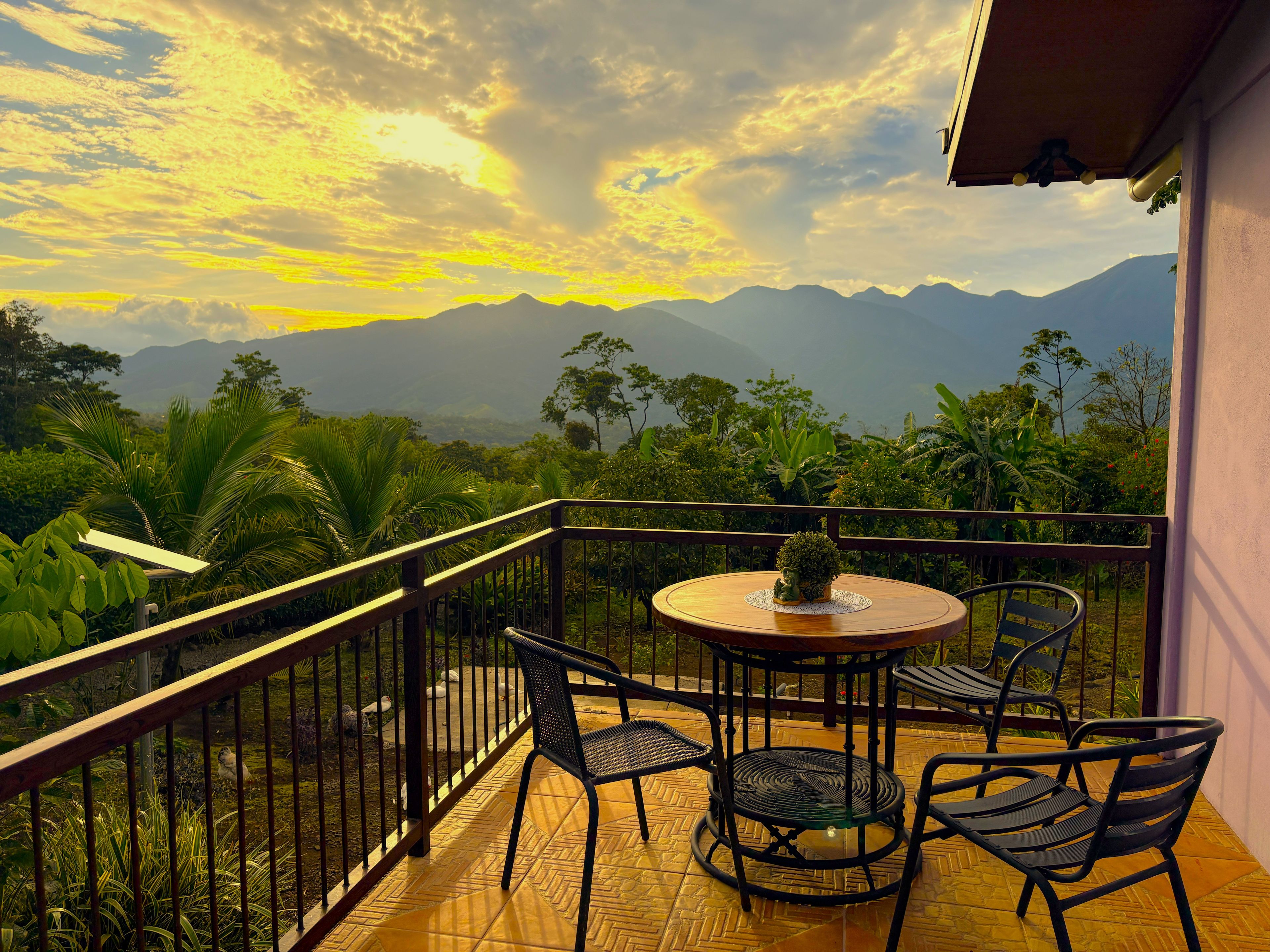 Un balcon avec une table ronde et des chaises, donnant sur un paysage montagneux.