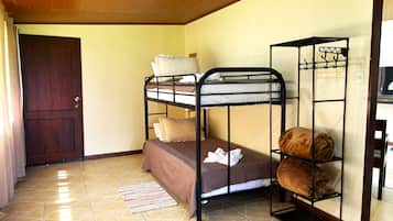 Um quarto com beliche, porta de madeira e chão de azulejos.