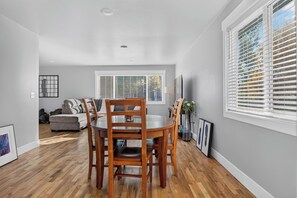 A dining area with a round table and chairs, a sofa, and a window with blinds. - Newly Remodeled 4 Bedroom Townhome for 8 Guests (Billings)