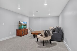 A living room with a flat-screen TV, a wooden cabinet, a sofa, and a coffee table. - Newly Remodeled 4 Bedroom Townhome for 8 Guests (Billings)
