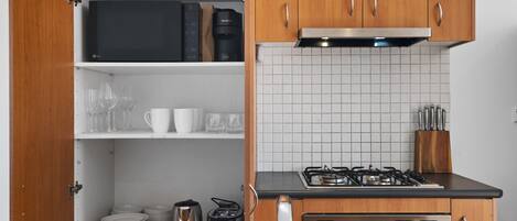 A modern kitchen with wooden cabinets, a gas stove, a microwave, and a sink.