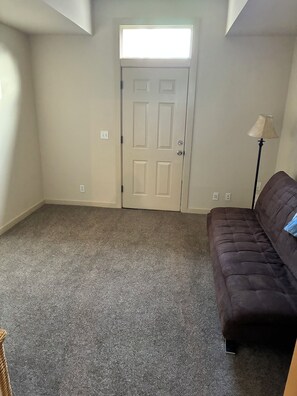 A room with a door, carpeted floor, and a brown sofa. - Nice 2-bedroom townhome with AC in pleasant Portland (Portland)