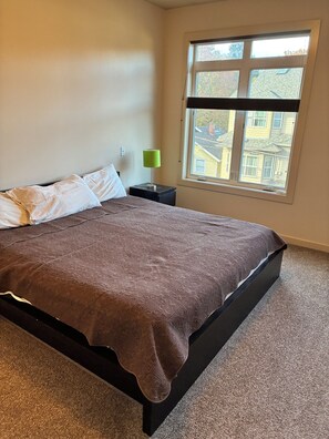 A bedroom with a bed, a nightstand, a lamp, and a window. - Nice 2-bedroom townhome with AC in pleasant Portland (Portland)