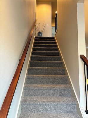 A carpeted staircase with wooden handrails and a potted plant at the top. - Nice 2-bedroom townhome with AC in pleasant Portland (Portland)
