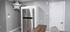 A modern kitchen with a stainless steel refrigerator, a wooden dining table, a white door, and a 'No Smoking' sign on the wall. - ATL Lakeview Haven - Private Suite & Deck (Decatur)