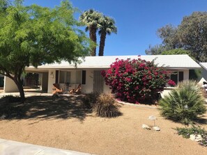 A residential house with a covered porch, a large tree, and a flowering bush. - Palm Desert Golf Course Home (Palm Desert)