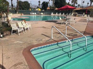 A swimming pool area with multiple lanes, lounge chairs, and a red umbrella. - Palm Desert Golf Course Home (Palm Desert)