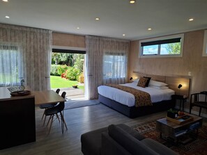 A modern bedroom with a large bed, a desk, and a dining area.