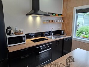 A modern kitchen with a microwave, stove, sink, and black cabinets.
