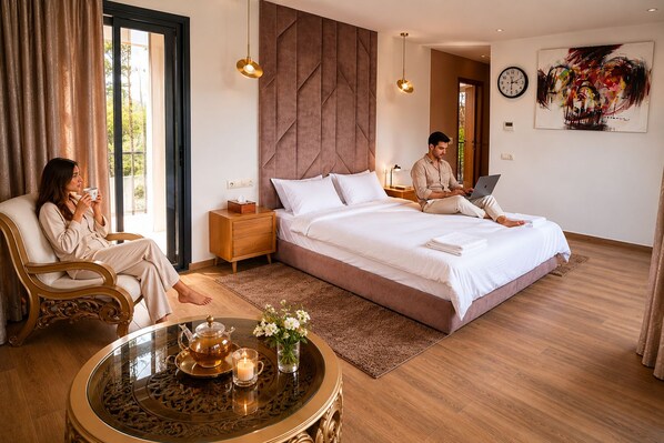 A modern bedroom with a large bed, bedside tables, a glass coffee table, and a view of the outdoors.