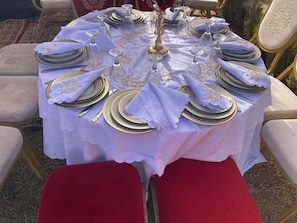A round table set for a meal with white tablecloth, gold and blue plates, and silverware.