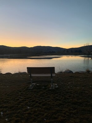 A bench overlooking a calm lake with a hilly landscape in the background. - Mountain Aloha in a magical location on the Eagle River (Edwards)