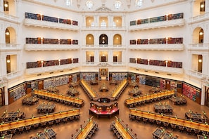 Een meerlaagse bibliotheek met talloze boekenplanken, leestafels en een centrale trap.