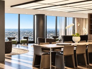 A modern dining area with a panoramic city view, large windows, and contemporary furniture. - Skyline Suites | Level 54 Sky Getaway, Gym & Pool (Southbank)