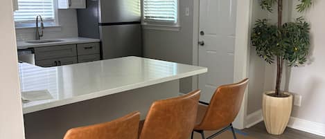 A kitchen with a white countertop, stainless steel appliances, and a potted plant.